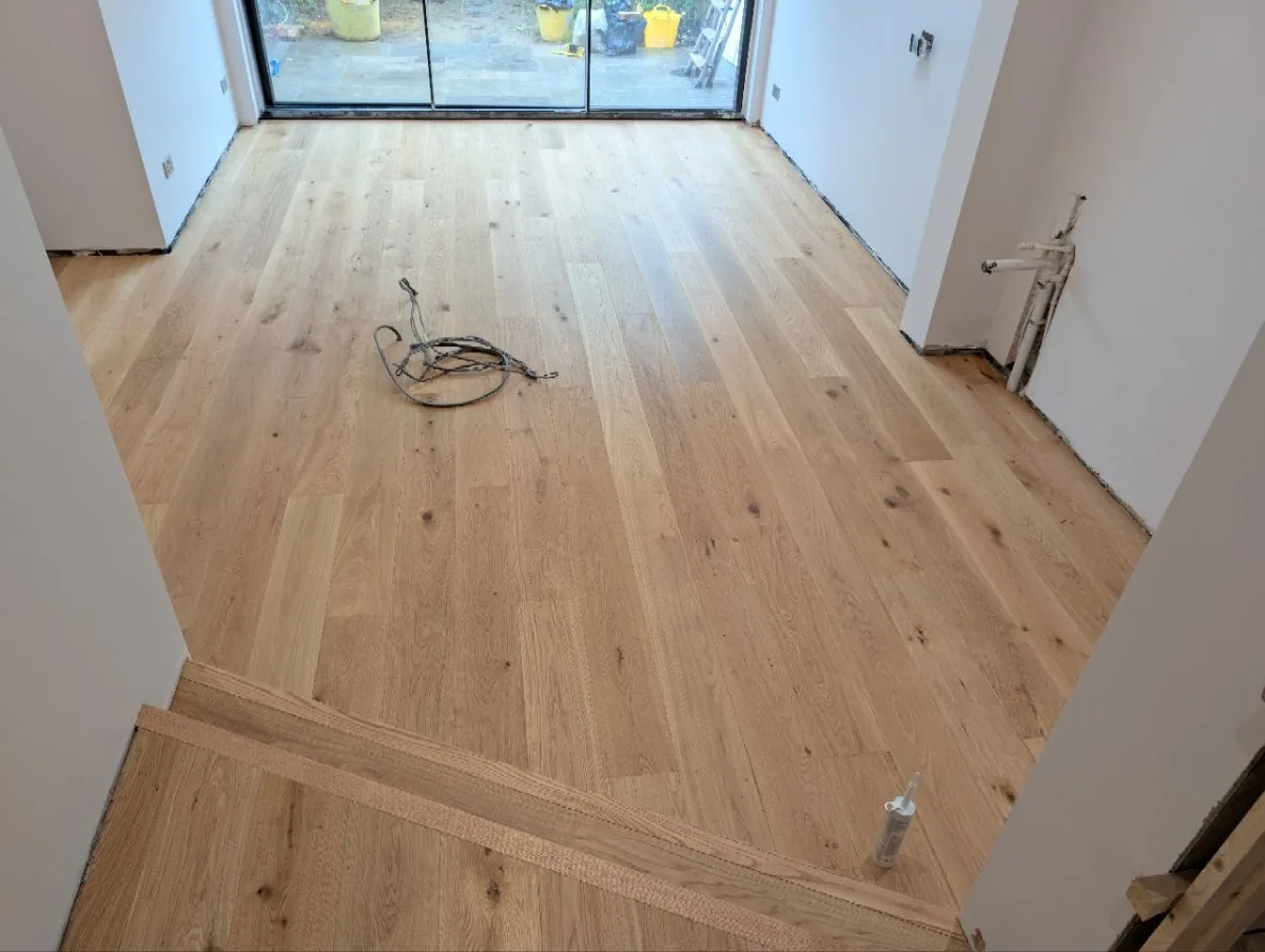 Wide natural oak floorboards running towards the glazed garden doors of a Dulwich extension