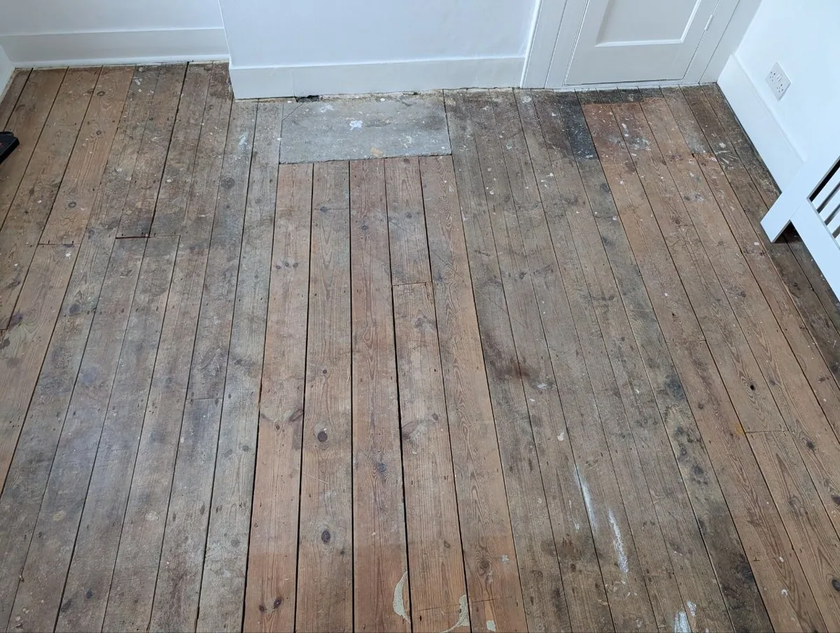 Original pine floorboards in a Lewisham house before sanding, dark with age and patched at the hearth